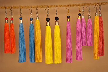 Fuarda renkli iplik küpeleri satılmaktadır. El yapımı takı bir ip üzerinde asılı.
