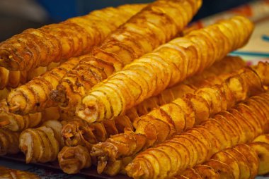 Bir sopanın üzerinde patates cipsi. Doğal cipsler kızartılır ve fuarda satılır. Yağlı sokak gıda.
