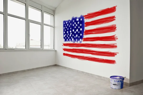 American flag painted with paints on white wall. United States national symbols in a room by the window. Concept of US patriotism and national values.