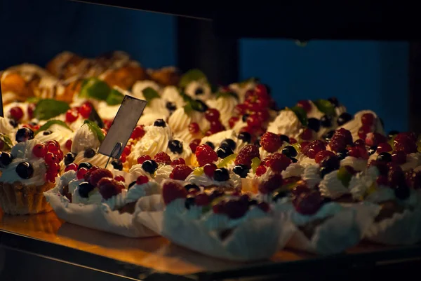 Multicolored round sweets at the shop window. Many cakes on a glass shelf.