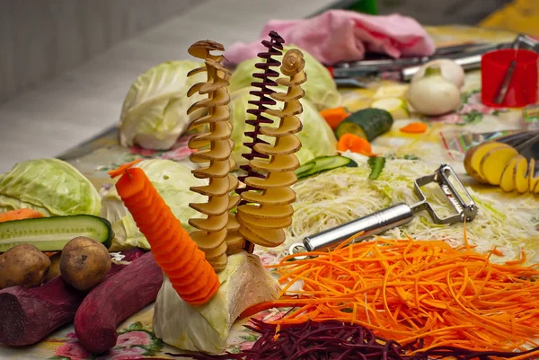 テーブルの上に野菜のスライスがたくさん 果物を細断するための台所用品のデモンストレーション 祭りで役に立つ食べ物 — ストック写真