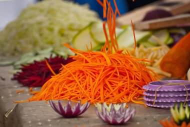 Masada bir sürü kesilmiş sebze var. Meyveleri öğütmek için mutfak aletleri gösterisi. Festivalde yararlı yemekler..