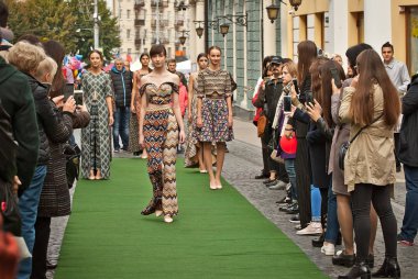 Ukrayna, Chernivtsi, Avrupa. 5 Ekim 2019. Moda gösterisi şehir gününü kutlamaya adanmıştır. Modeller yeşil yolda yürürler ve insanlar telefonlarıyla fotoğraflarını çekerler..