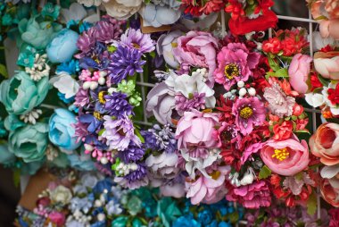 Panayırda yapay çiçek buketleri satılıyor. Renkli küçük çiçeklerden yapılmış korolalar. Ulusal dekorasyon ve giysi aksesuarlarının kapatılması.