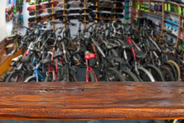 Mockup. Image of sport store with bike. Defocused, blurred image. In the foreground is the top of a wooden table, counter.