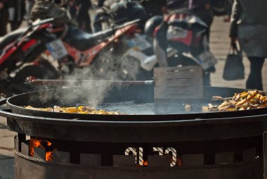 Büyük bir tavada kızarmış patates. Motosiklet festivali arka planında ızgara sebze. Arka planda bulanık motosikletler var. Motorcular için park etmek. Motosiklet besin değişimi.
