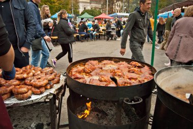 Ukrayna, Chernivtsi. 5-6 Ekim 2019. Şehir Festivali. Kömürde ızgara kızartma. Bulanık insanlar arka plandaki masada yemek yerler. Mutfak festivalinde et ve et.