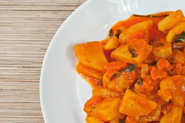 Tahta bir masada beyaz bir tabakta patates. Portakal soslu haşlanmış patates. Yazı için plakaya yakın bir yere. Tasarım için alanı kopyala.