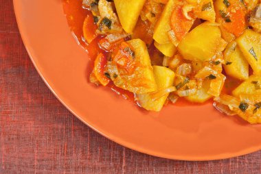 Tahta bir masada sarımsak tabağında patates. Portakal soslu haşlanmış patates..