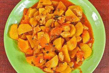 Tahta bir masada yeşil tabakta patates. Kırmızı tahtada portakal soslu haşlanmış patates.. 