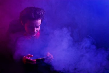 Kulaklıklı adam telefonda çalıyordu. Arka planda kırmızı ve mavi karıncalanma olan kalın duman. Sanatsal bir etki olarak yüzüne çarpıcı bir zıt ışık vuruyor..