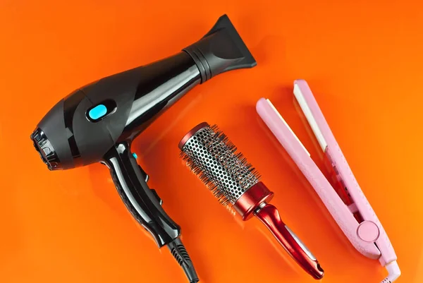 Hairdryer, comb, scissors  isolated on a orange background. Layout for design. Mockup