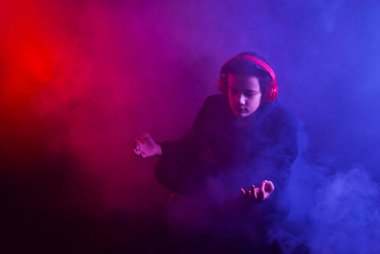 Adam siyah arka planda yoğun duman içinde meditasyon yapıyor. Kırmızı ve mavi renkli duman. Sanatsal bir etki olarak dramatik zıt gölgeler. Lotus pozisyonunda oturan adam.