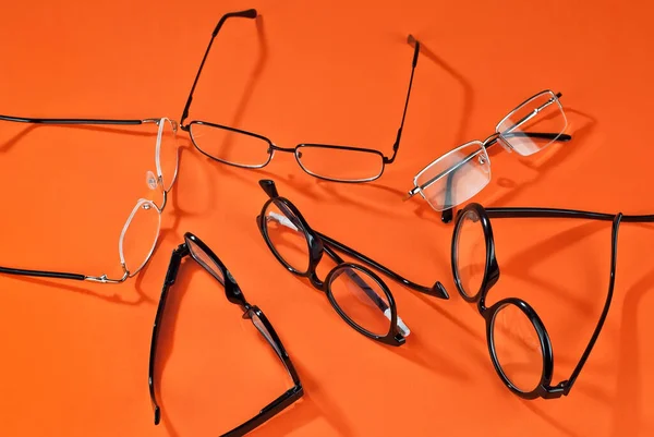 Různé Typy Brýlí Oranžovém Pozadí Zblízka Brýle Obdélníkovými Kulatými Rámy — Stock fotografie
