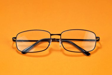 Sarı arka planda farklı tipte gözlükler var. Dikdörtgen çerçeveli gözlük.