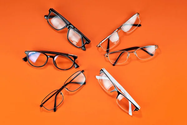 Různé Typy Brýlí Oranžovém Pozadí Zblízka Brýle Obdélníkovými Kulatými Rámy — Stock fotografie