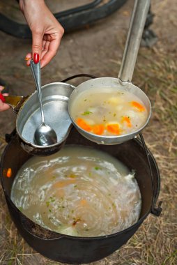 Balık çorbası ateşte pişirilir. Doğada demir bir kasede kulaklar.