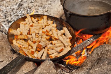 Ateşin üstünde yağlı Rusklar pişiyor. Birçok kraker kamp koşullarında kızarır. Kuru ekmeğin dokusu kapat.