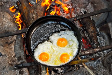 Üç yumurtalı bir omlet ateşte kızarır. Yumurtalar yürüyüş sırasında tavada pişirilir..