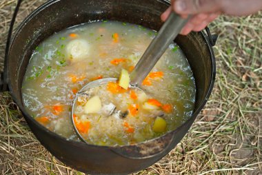 Balık çorbası ateşte pişirilir. Doğada demir bir kasede kulaklar.
