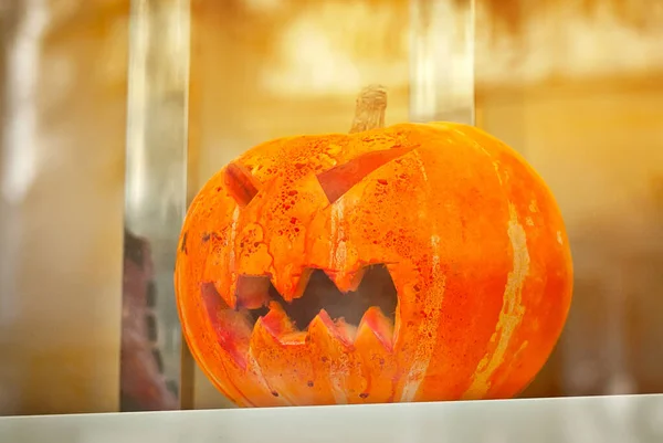 Pumpkin with carved eyes in a shop window. Halloween symbols behind a glass shop window.