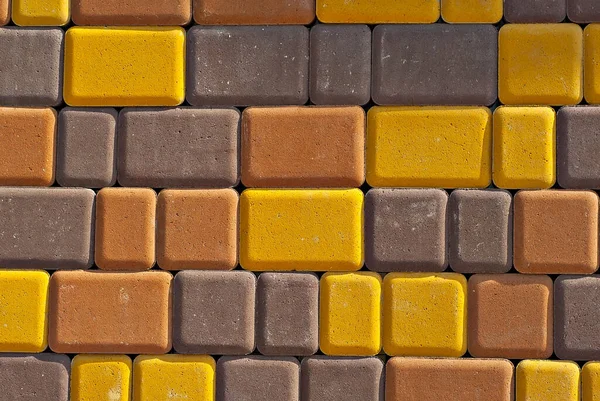 Cobblestone texture. The sidewalk tile is evenly folded. Brown, yellow and orange cobblestones close up.