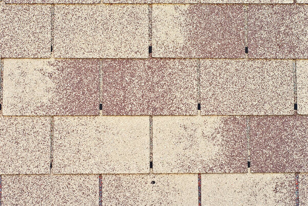 Flexible tile is made of fiberglass impregnated with bitumen. Yellow and brown roof texture close up.
