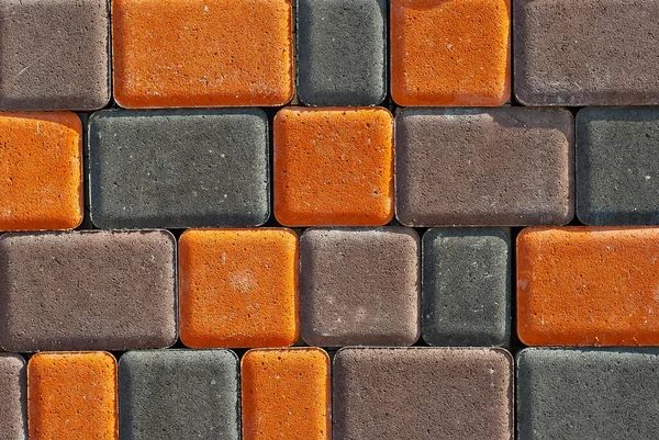 Cobblestone texture. The sidewalk tile is evenly folded. Brown and orange cobblestones close up.