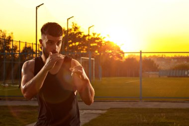 Sporcu gün batımında antrenman yapar. Boksör stadyumun yakınında ısınıyor. Yüzündeki dramatik gölgeleri sanatsal bir etki olarak görüyor. Çocuk parkındaki adam..