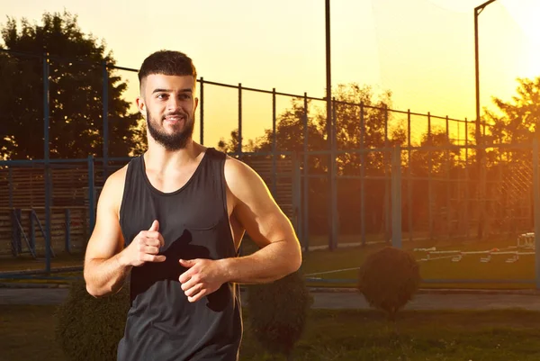 A man runs on the playground. Athlete on a sunset background.