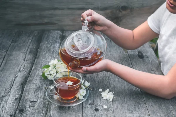 The girl pours hot tea in a transparent glass Cup.