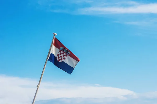 Croatian flag flying on wind, blue sky with clouds in background.