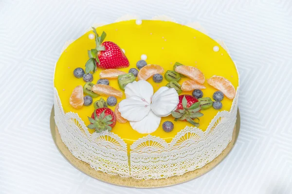 Beautiful delicious yellow cake with fruit and caramel decorations with a smooth jelly surface.