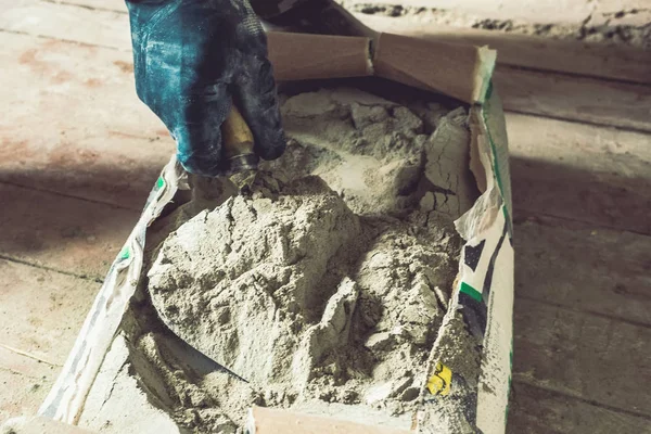 Cement powder in the cement bag, a hand hold the trowel scoop cement powder cray for construction work