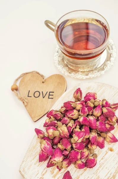 Rose Bud tea . Tea from rose buds is made of real rose buds, plucked in youth, and then dried. A Cup of tea and a wooden heart with the words I love you