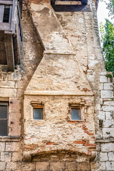 The original fake fireplace on the wall of a house. Decorative pattern. Decoration of a stone wall with Windows in the form of a fireplace