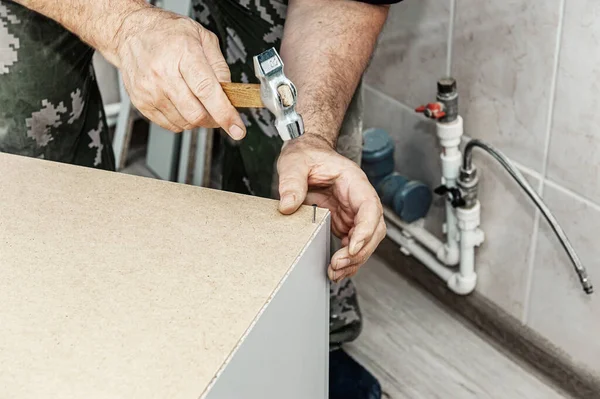 master collects furniture. Close-up of a master hammering a nail into a wooden Board. Concept of repair and renovation