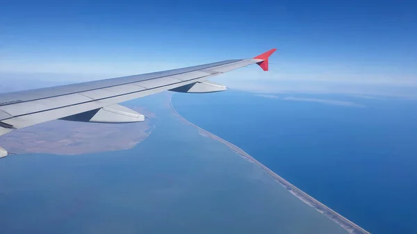 airplane wing above the clouds. Black sea coast view from the plane.