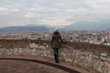 İtalya, Brescia-31 Aralık 2017: Brescia cityscape Castle'nın kuleden üzerinde 31 Aralık 2017 Brescia, Lombardiya, İtalya izlerken genç bir kadın görünümünü.