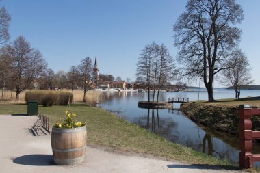 Baharda Gripsholm Kalesi yakınlarında güneşli bir günde çıplak ağaçlar ve göl manzarası, Mariefred, İsveç.