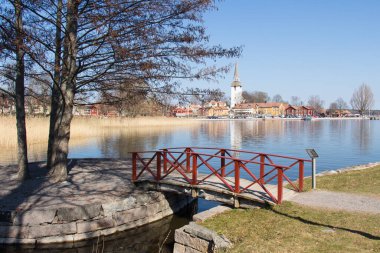 Mariefred, İsveç - 20 Nisan 2019: İsveç 'in Mariefred kentinde 20 Nisan 2019 tarihinde Mariefen Gölü kıyısında kurulan kırmızı köprü ve İsveç kenti manzarası.
