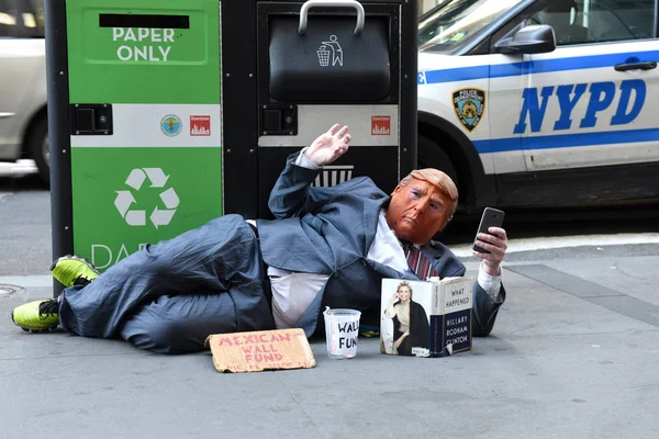 2018年5月30日 街头乞丐戴着王牌面具和阅读希拉里 克林顿的书发生了什么事 该名男子嘲弄现任美国总统 并要求游客为墨西哥边境墙提供资金 — 图库照片