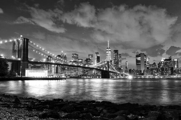New York City, financial district in lower Manhattan with Brooklin Bridge at night, USA. BW
