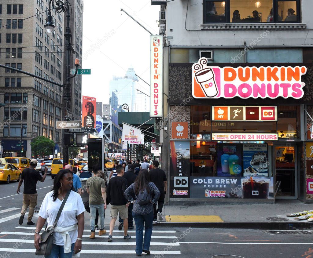 New York, USA - May 27, 2018: People on the street near the Dunkin' Donuts in New York.