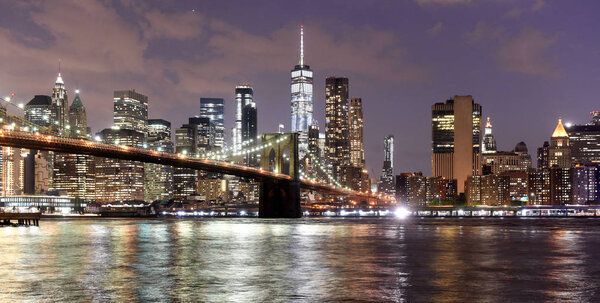 New York City, financial district in lower Manhattan with Brooklin Bridge at night, USA