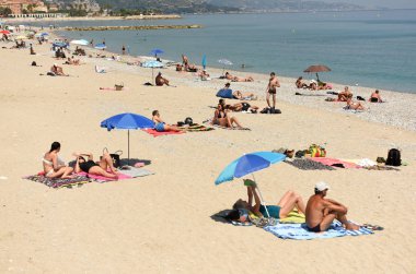 Menton, Fransa - 18 Haziran 2019: Fransız Rivierası'nın Cote d'Azur'undaki Menton sahilinde insanlar dinleniyor.