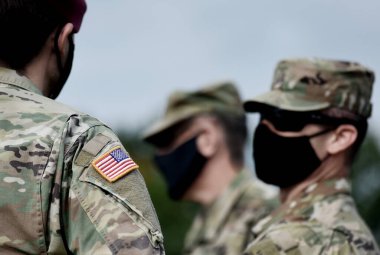 Asker kolunda Amerikan bayrağı ve koruyucu maskeler takan Amerikan askerleri. Orduda karantina. Amerika Birleşik Devletleri 'nin askeri güçleri.