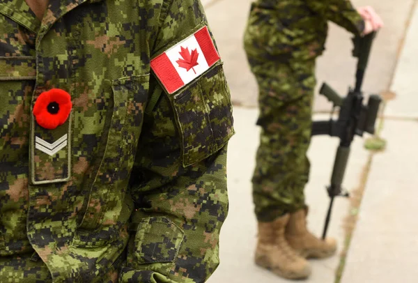 Flag of Canada on the military uniform and soldier with weapon on the background. Canadian soldiers. Canadian Army. Remembrance Day.Poppy day.