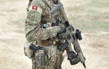 Soldier with assault rifle and flag of Switzerland on military uniform. Collage. 