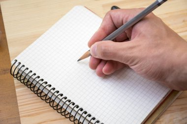 Adam bir şey yerleştirilmiş masaya not defterinde çizim